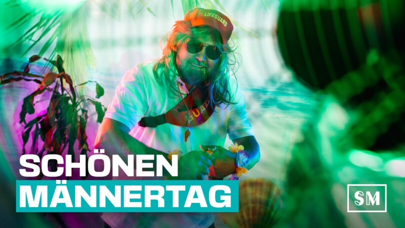 Mario Kattner beim Sommershooting, mit Sonnenbrille und Baywatchoutfit in rosa-grünem Studiolicht