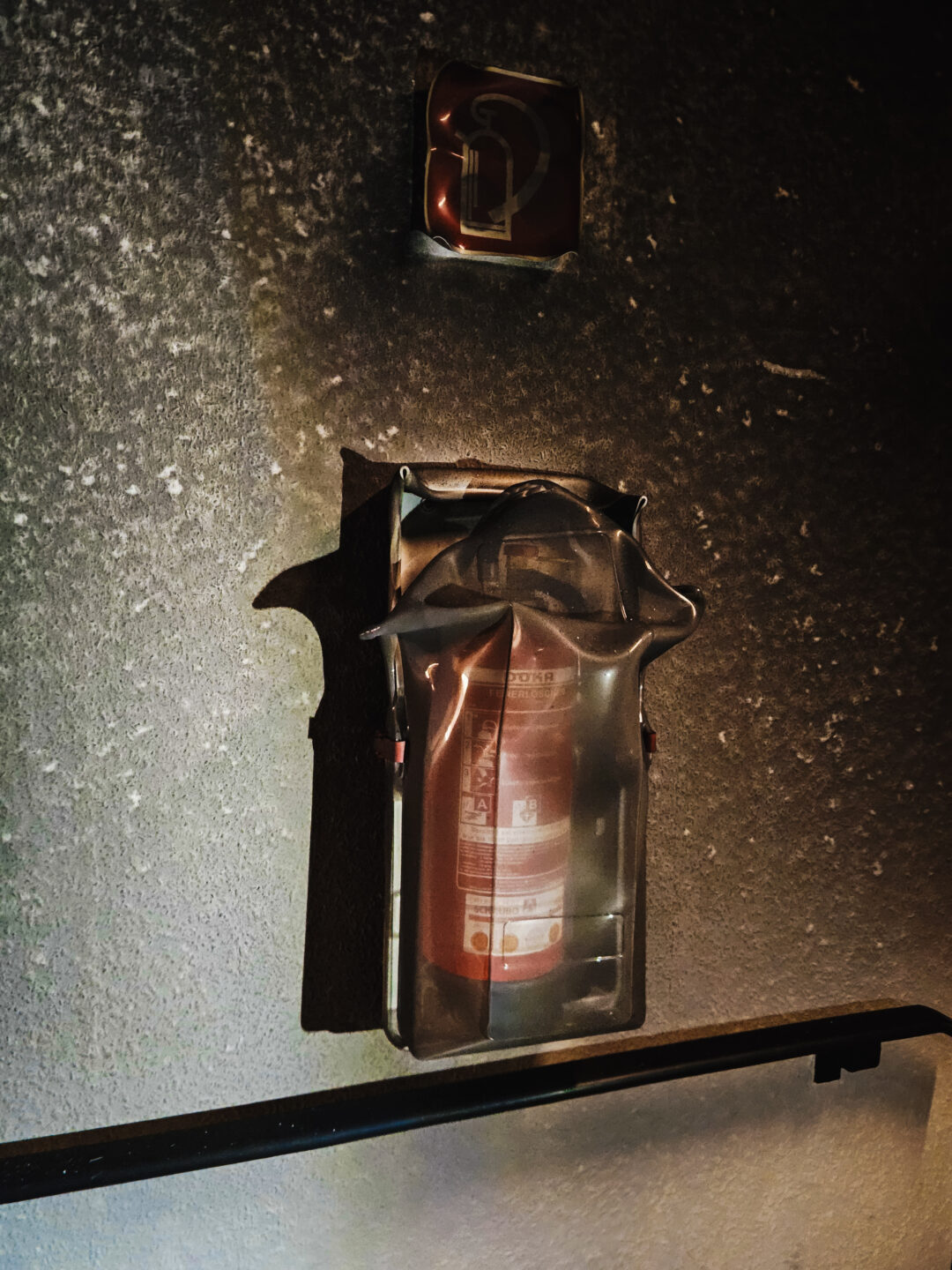 geschmolzener behalter an der Wand mit der Löschflasche darin