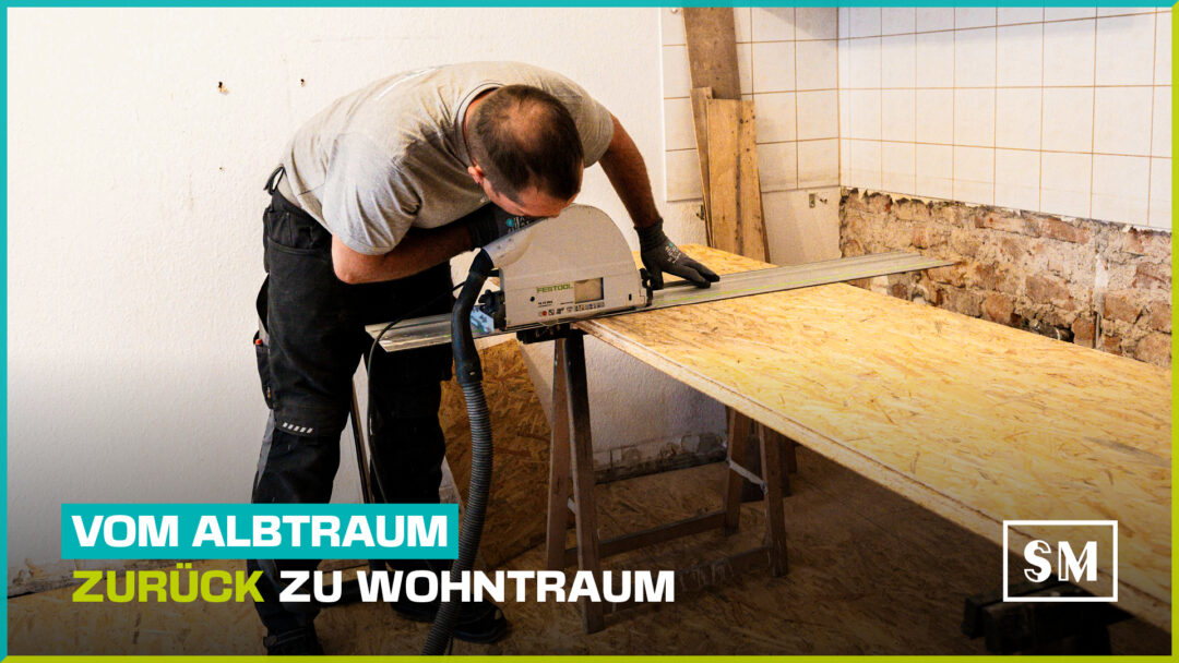 Ein Bauarbeiter beugt sich über eine große OSB-Platte, die auf zwei Sägeböcken liegt, und schneidet sie mit einer Festool Tauchsäge entlang einer Führungsschiene zu. Er trägt ein graues T-Shirt und Arbeitshosen. Der Raum ist eine Baustelle mit teilweise gefliesten, aber beschädigten Wänden und freigelegtem Mauerwerk im unteren Bereich. Ein türkisfarbener und schwarzer Text-Overlay dominiert das untere Bilddrittel: "VOM ALBTRAUM ZURÜCK ZU WOHNTRAUM". Rechts unten ist das Logo "SM" zu sehen.
