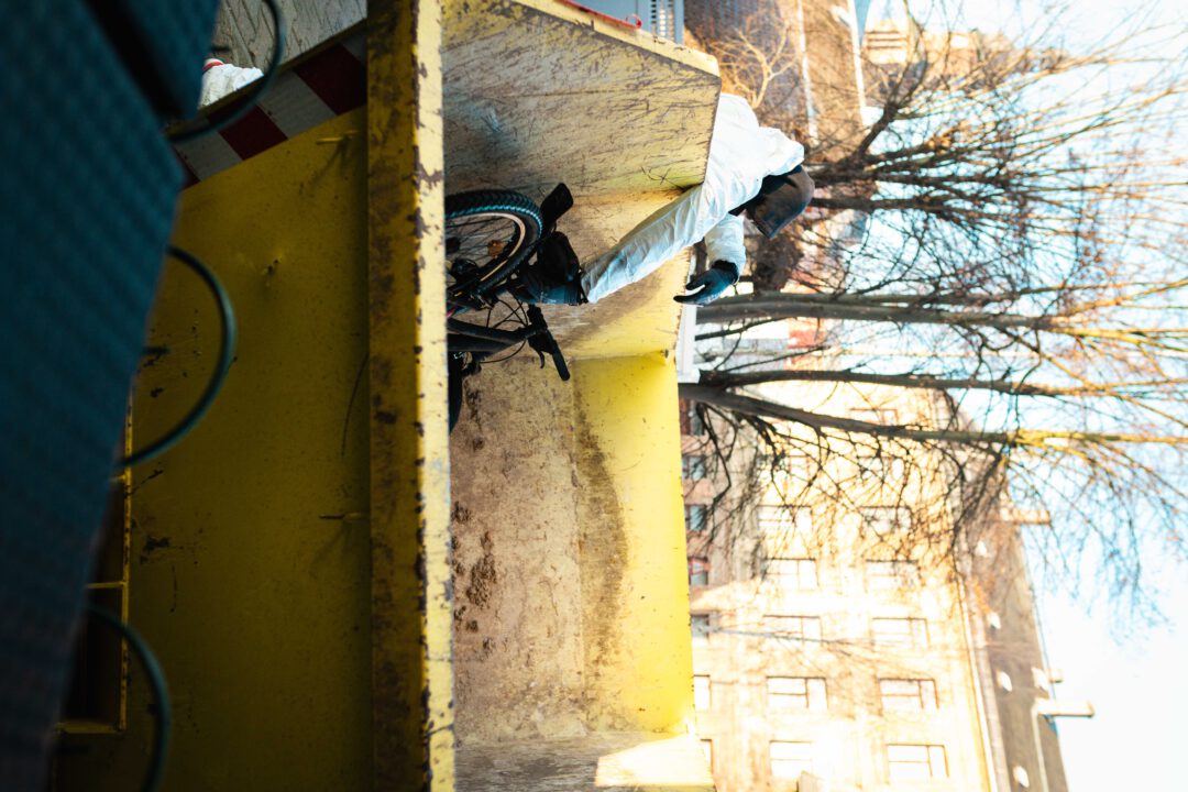 Fachgerechte Entsorgung: Ein durch Ruß und Feuer beschädigtes Fahrrad wird während der Aufräumarbeiten im Container entsorgt.