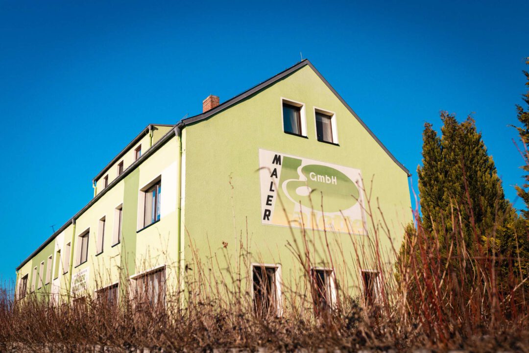 Fassadengestaltung Firmengebäude: Seitenansicht des Gebäudes der Maler Palette GmbH mit großflächigem Firmenlogo an der grünen Fassade.