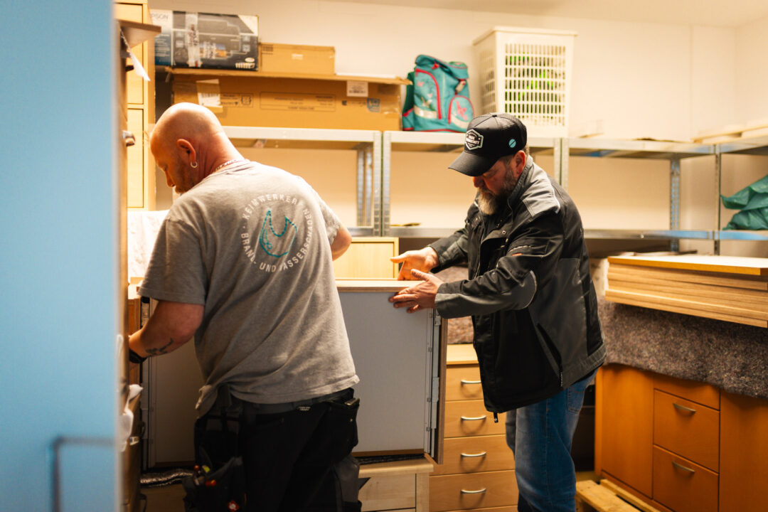Zwei Mitarbeiter, Mike und Chef Mario Kattner, der SM Kattner Sanierung beim vorsichtigen Transport und der Einlagerung von Möbeln nach einem Wasserschaden.