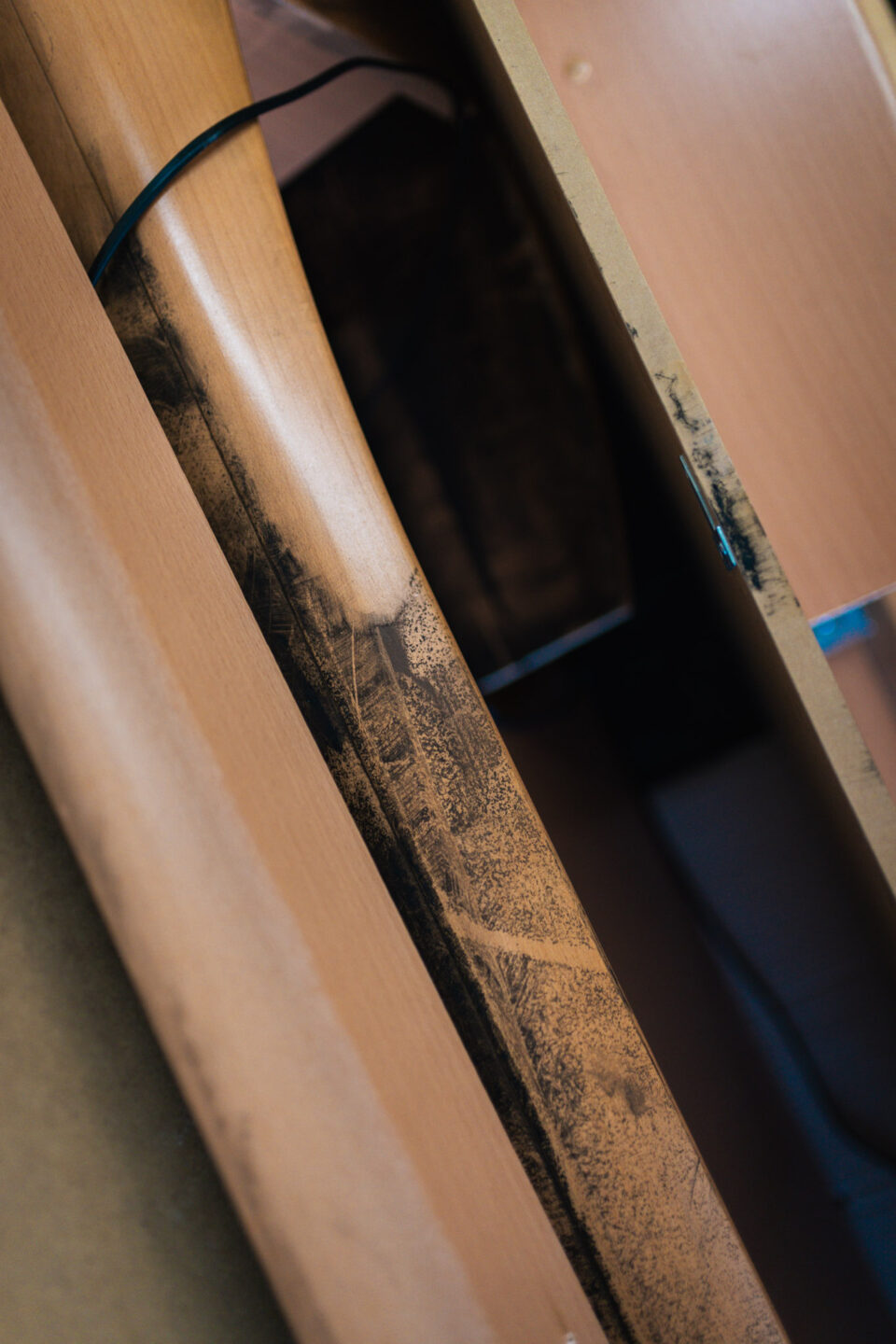 Detailaufnahme von Rußablagerungen und Brandspuren auf einer Holzoberfläche vor der Restaurierung.