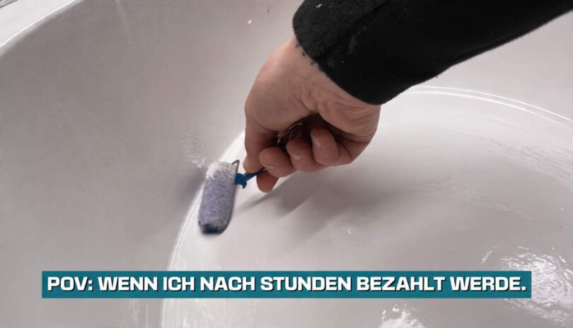 Hand mit Mini-Maler-Walze in einem riesigen Topf weißer Malerfarbe.