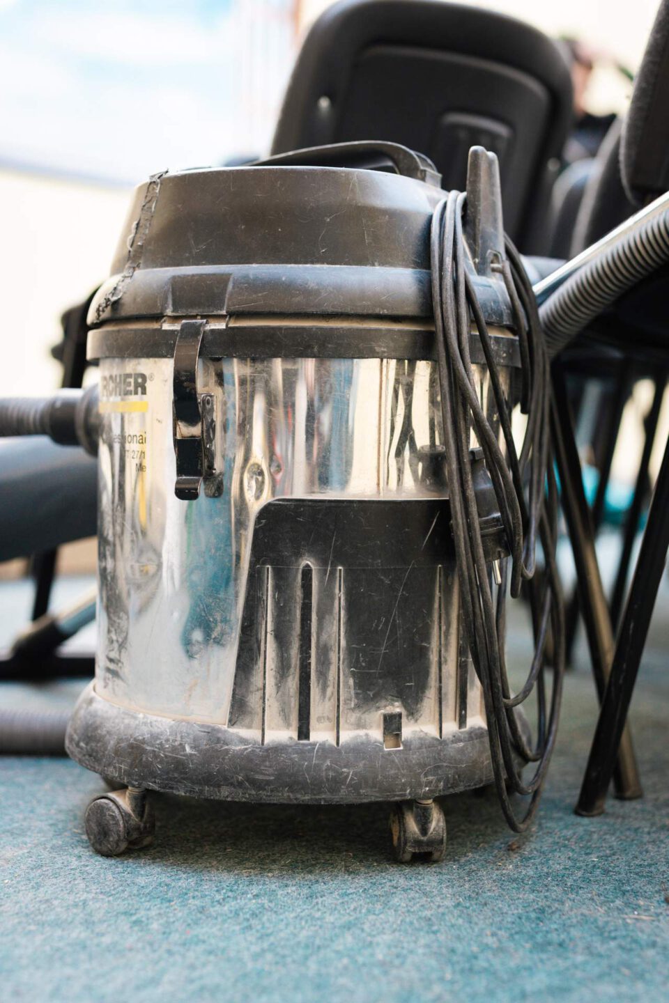 Ein industrieller Kärcher-Nass-Trockensauger für die professionelle Rußbeseitigung und Brandschadensanierung steht einsatzbereit neben gereinigten Stühlen in einem Klassenzimmer.