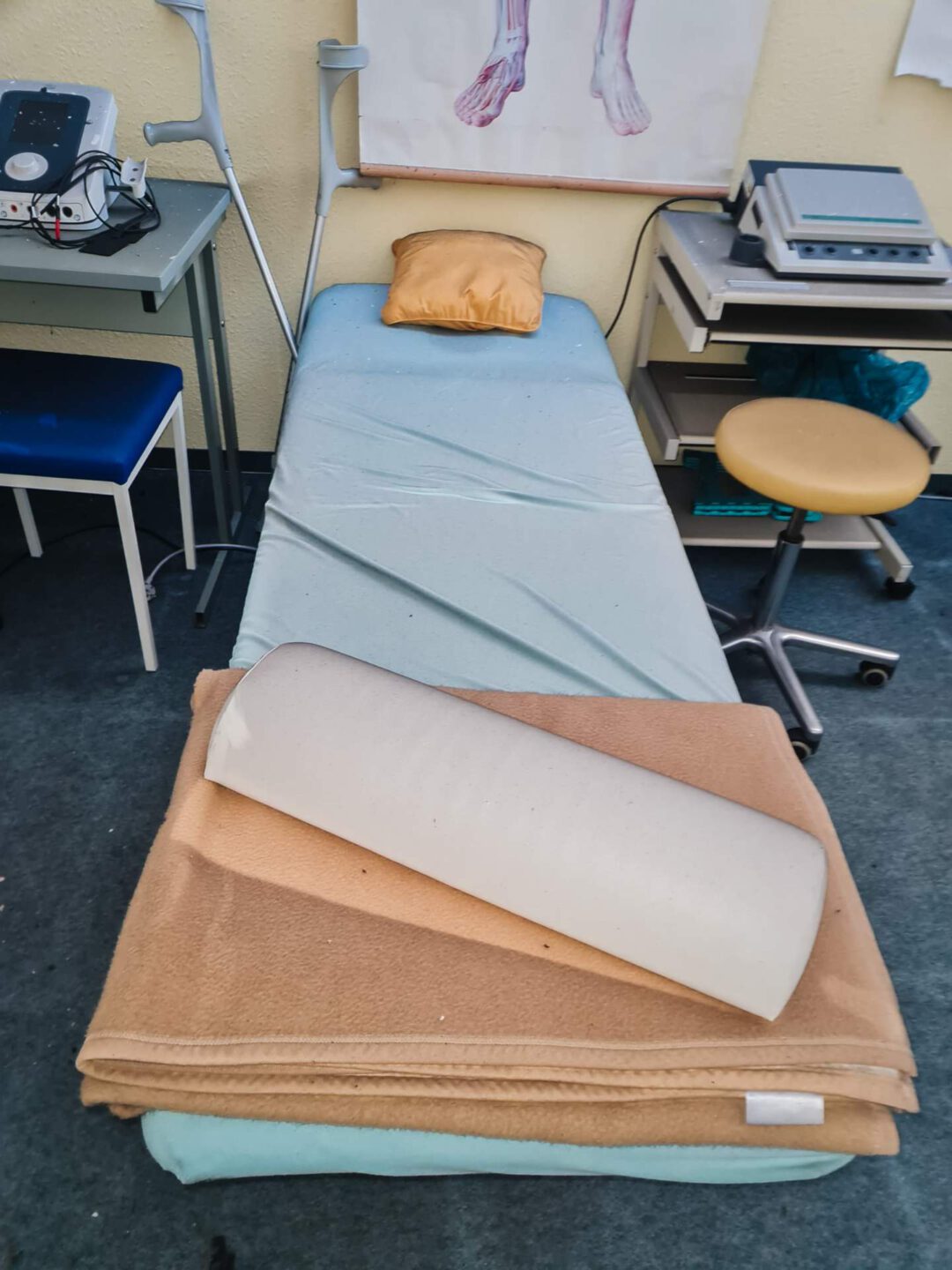 Eine medizinische Behandlungsliege mit einer Decke und einer Nackenrolle in einem Physiotherapie-Raum vor Beginn der aufwendigen Brandschaden-Spezialreinigung.